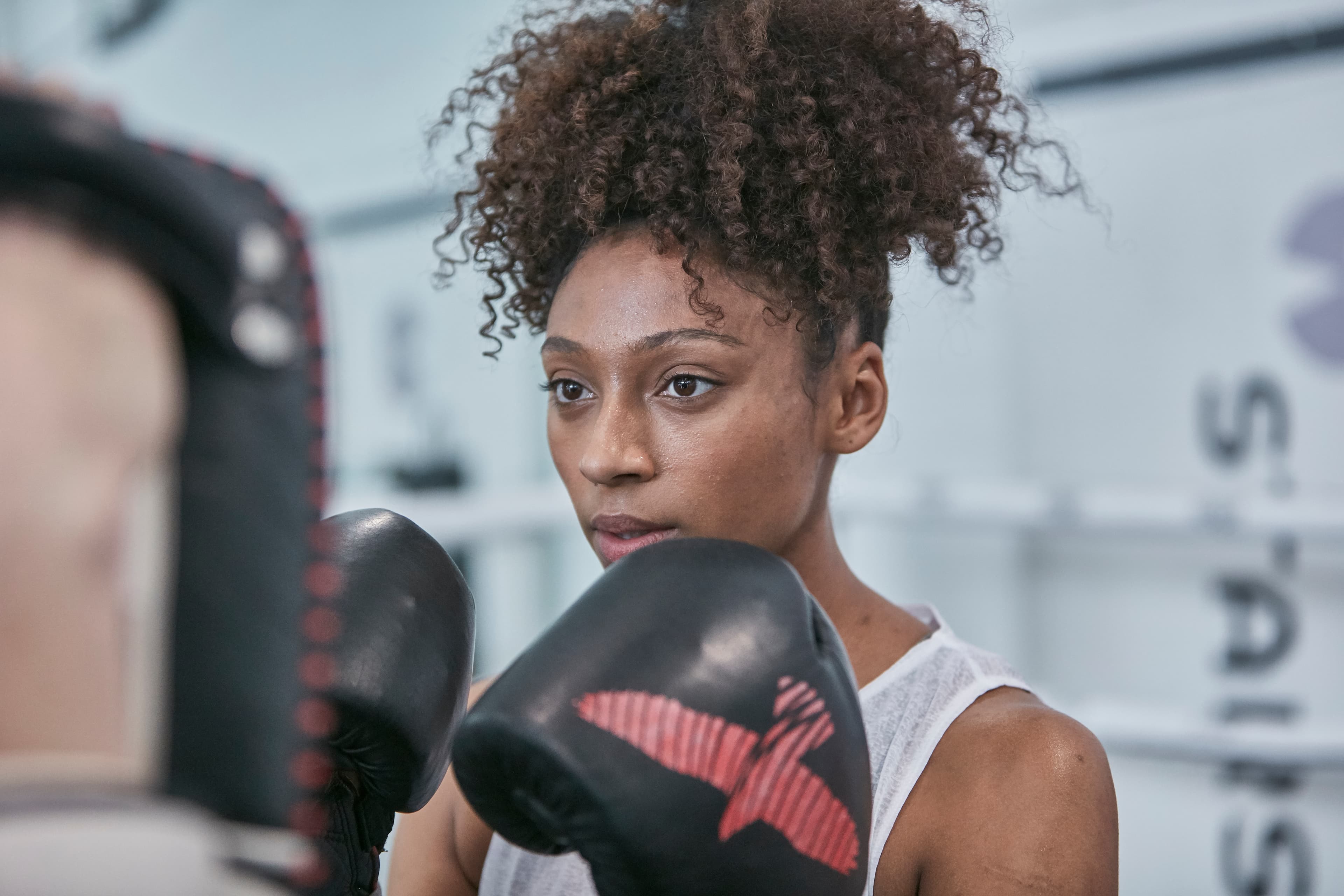 Two employees wearing Hussle t-shirts sit next to each other in front of a boxing ring, smiling at the camera.