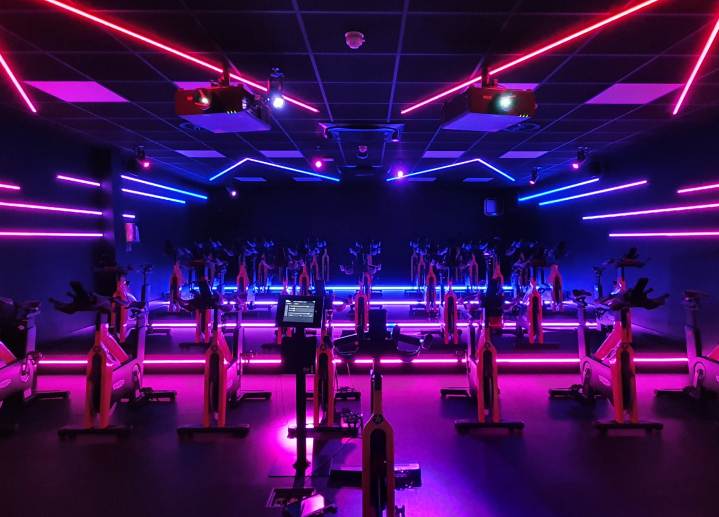 A high-tech spinning studio lit in purple and blue