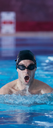 A man wearing goggles and swimming cap swimming towards the camera.